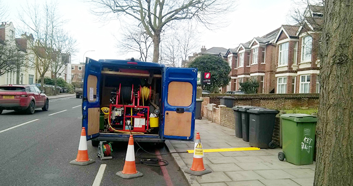 knk van parked on the road with with back doors and cones around